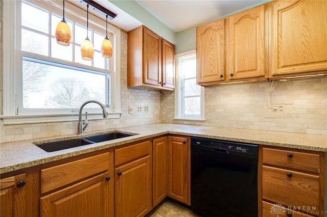 kitchen featuring pendant lighting, sink, light stone counters, and dishwasher