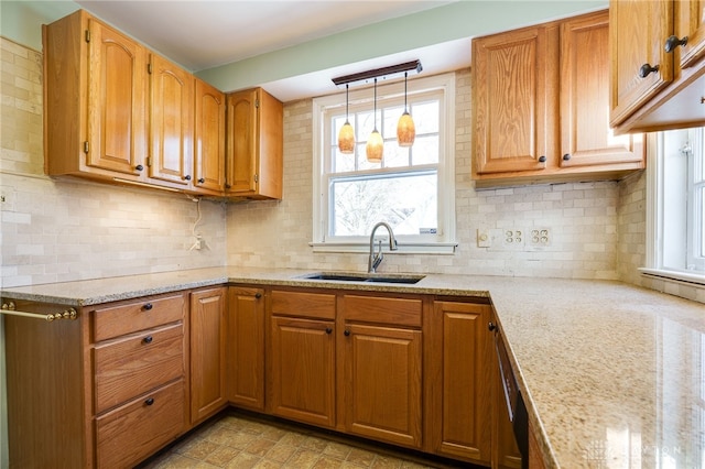 kitchen with light stone countertops, sink, decorative backsplash, and decorative light fixtures