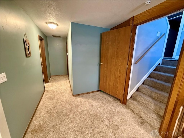 hall featuring light colored carpet and a textured ceiling