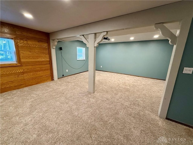 basement featuring carpet flooring and wood walls