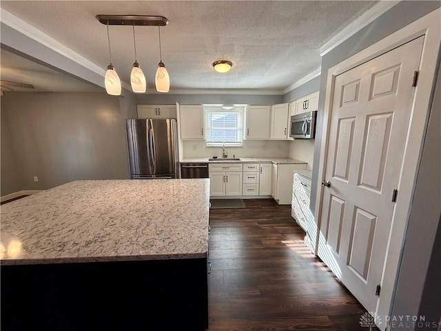 kitchen featuring sink, white cabinets, hanging light fixtures, stainless steel appliances, and light stone countertops