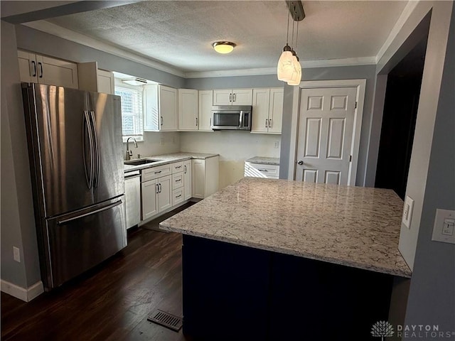 kitchen with white cabinetry, hanging light fixtures, light stone counters, and appliances with stainless steel finishes