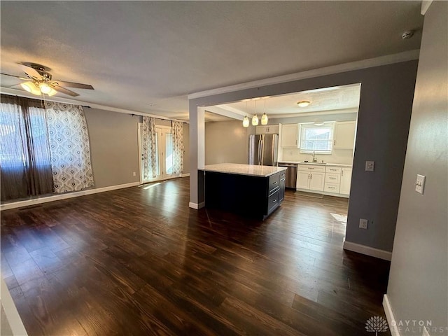 kitchen with sink, stainless steel appliances, a center island, white cabinets, and decorative light fixtures