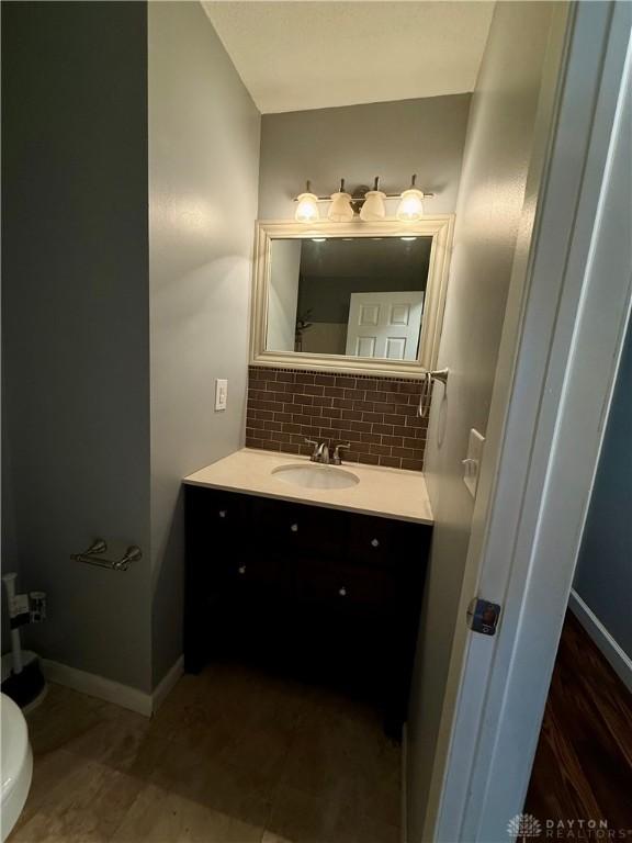 bathroom featuring vanity, decorative backsplash, and toilet