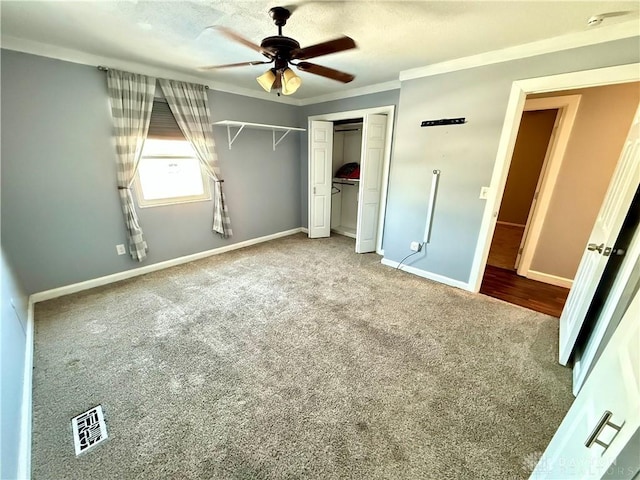 unfurnished bedroom with crown molding, carpet flooring, ceiling fan, and a closet