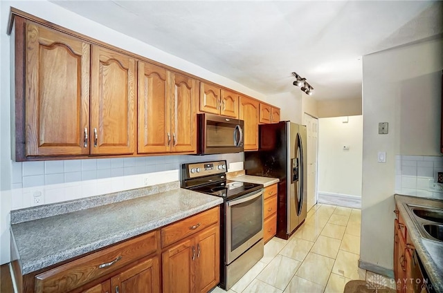 kitchen with light tile patterned flooring, appliances with stainless steel finishes, sink, and decorative backsplash