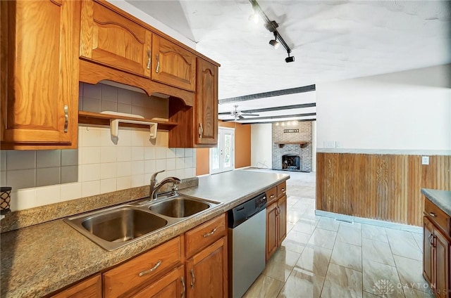 kitchen with rail lighting, sink, dishwasher, ceiling fan, and a fireplace