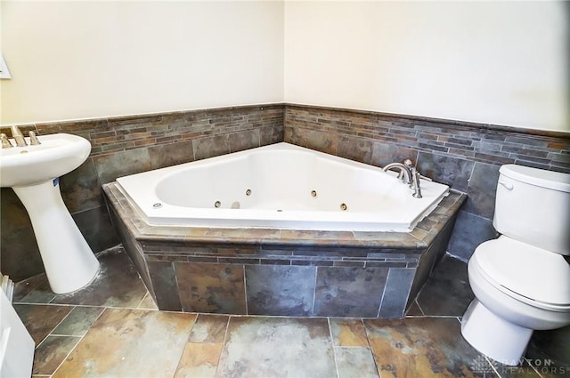 bathroom featuring a relaxing tiled tub and toilet