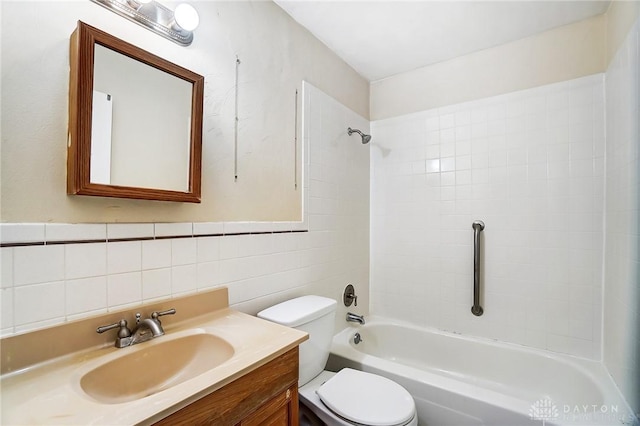 full bathroom with tiled shower / bath, tasteful backsplash, tile walls, vanity, and toilet