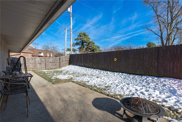 snow covered patio with an outdoor fire pit