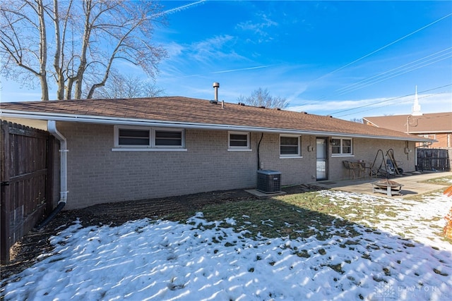 snow covered rear of property with central AC, a patio, and a fire pit