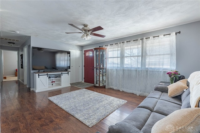 living room with dark wood-type flooring, ceiling fan, and a textured ceiling