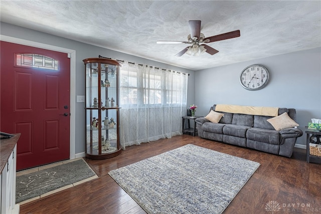 living room featuring ceiling fan, dark hardwood / wood-style flooring, and a textured ceiling