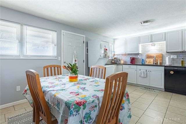 tiled dining room with stacked washing maching and dryer, sink, and a textured ceiling