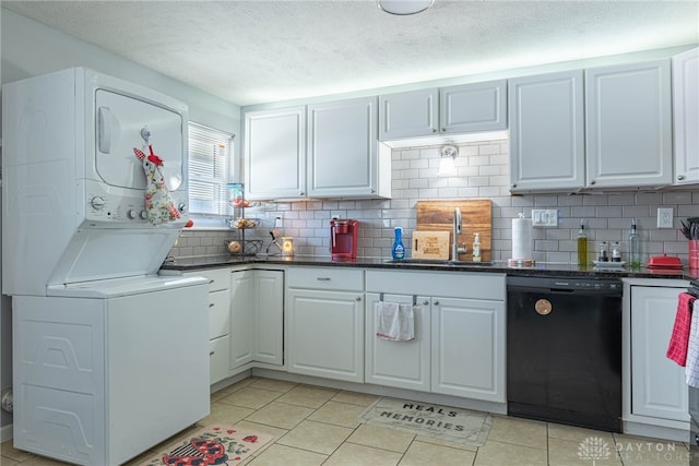 kitchen with white cabinets, light tile patterned floors, black dishwasher, and stacked washer / dryer