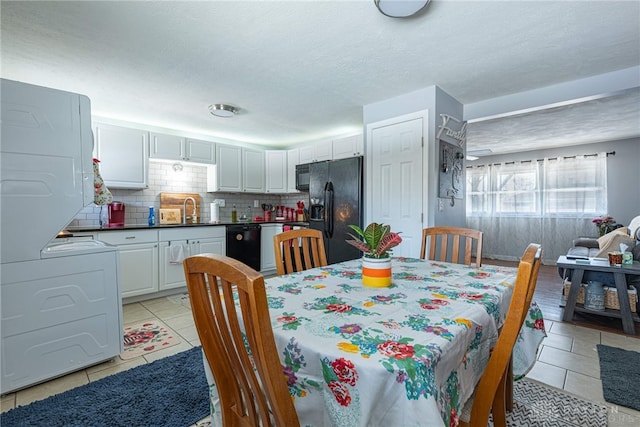 tiled dining space with stacked washing maching and dryer, sink, and a textured ceiling