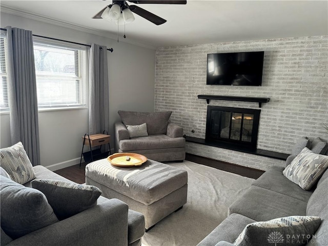 living room featuring brick wall, hardwood / wood-style flooring, ornamental molding, ceiling fan, and a brick fireplace