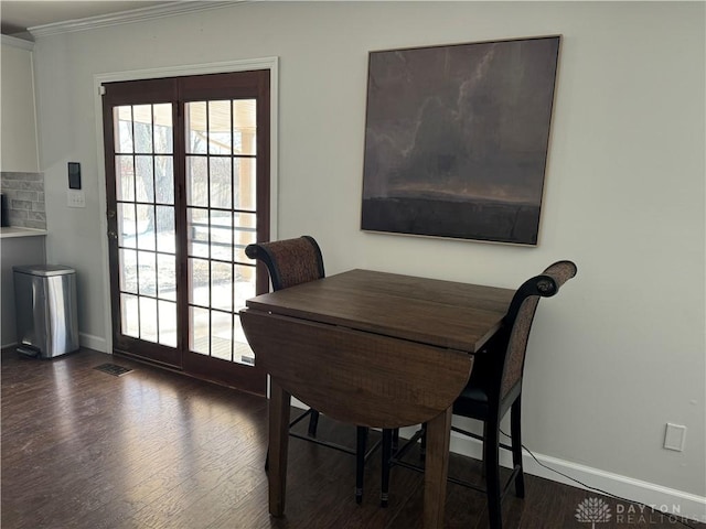 dining area with dark wood-type flooring and ornamental molding