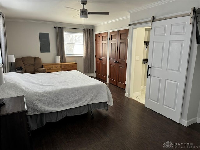 bedroom featuring ornamental molding, a barn door, dark wood-type flooring, and electric panel