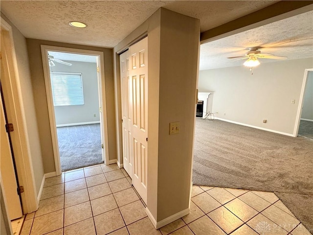 hall featuring light carpet and a textured ceiling