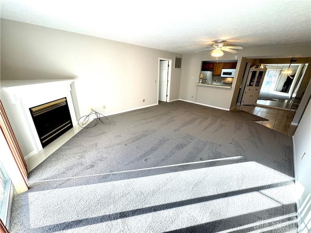 unfurnished living room featuring ceiling fan, carpet floors, and a textured ceiling