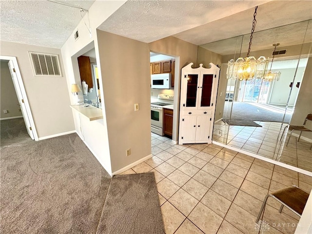 kitchen featuring decorative light fixtures, light colored carpet, a textured ceiling, a notable chandelier, and white appliances