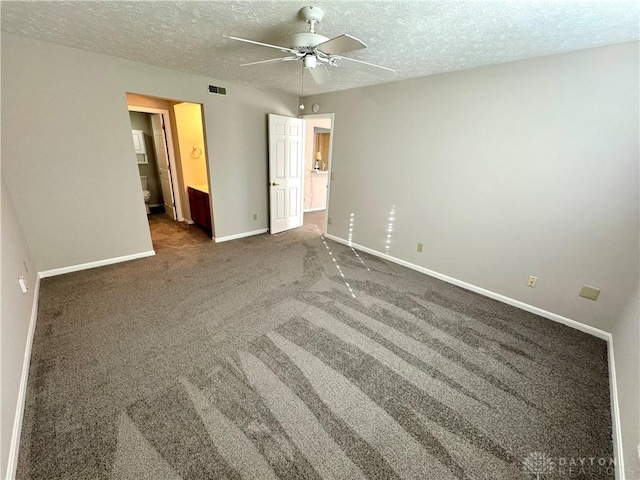 unfurnished bedroom featuring ceiling fan, ensuite bath, dark carpet, and a textured ceiling