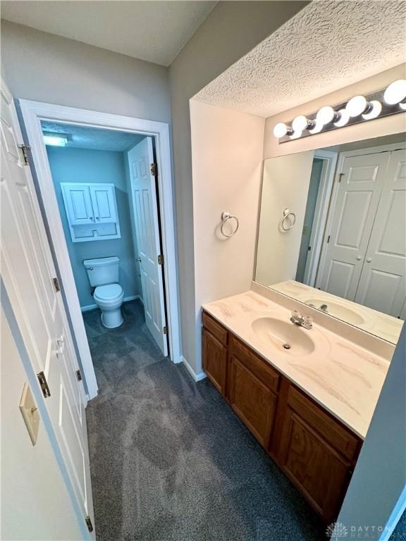 bathroom with vanity, a textured ceiling, and toilet