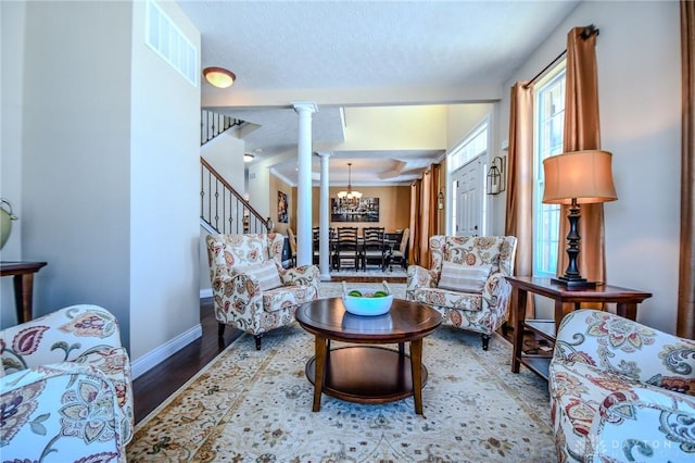 living room with an inviting chandelier, hardwood / wood-style floors, and decorative columns