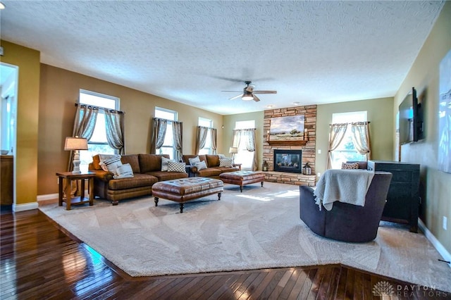 living room featuring ceiling fan, a fireplace, hardwood / wood-style floors, and a textured ceiling