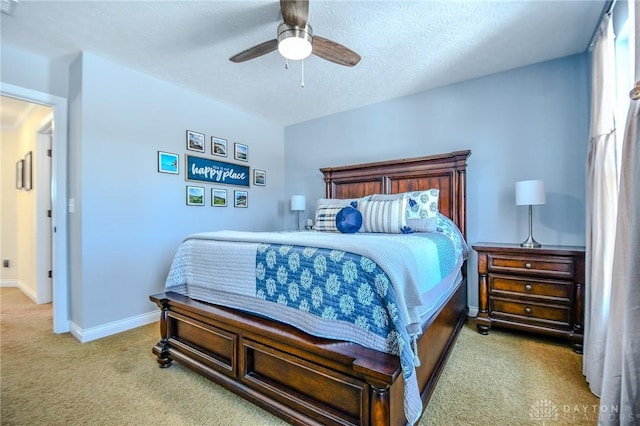 bedroom with ceiling fan, light carpet, and a textured ceiling