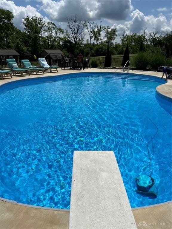 view of pool with a diving board and a patio area