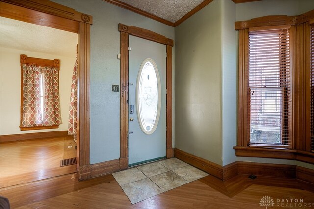 entryway with ornamental molding and light wood-type flooring