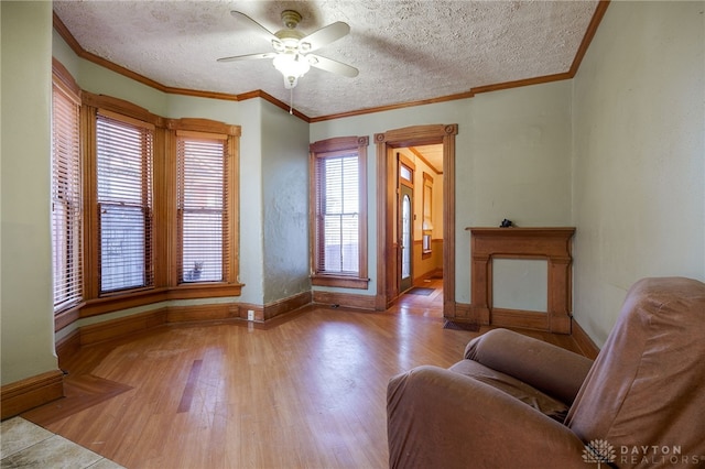 sitting room with ceiling fan, crown molding, light hardwood / wood-style floors, and a textured ceiling