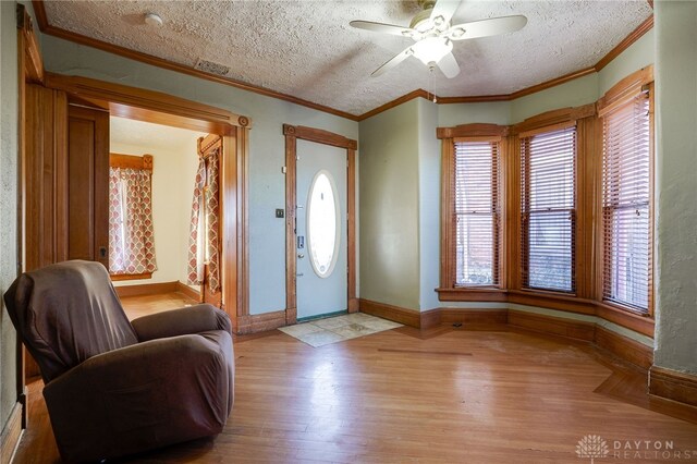 entryway featuring crown molding, light hardwood / wood-style flooring, and a textured ceiling