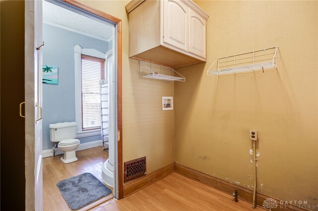 laundry room with hookup for a washing machine, a textured ceiling, and light wood-type flooring