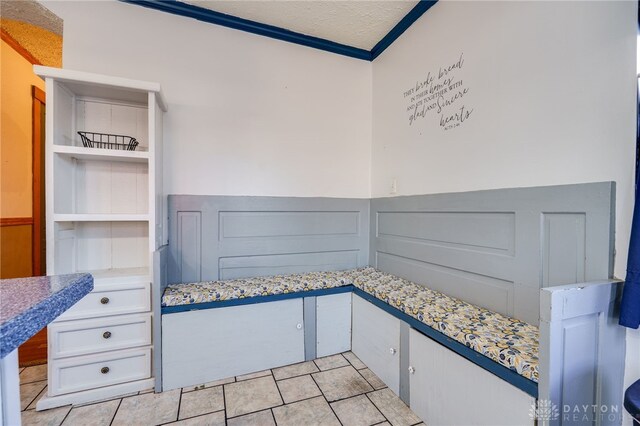 interior space featuring crown molding, built in desk, a textured ceiling, and light tile patterned floors