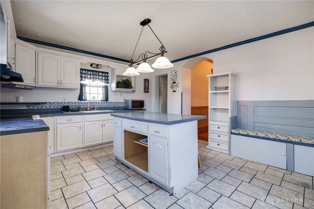 kitchen with white cabinets, hanging light fixtures, a center island, and a textured ceiling