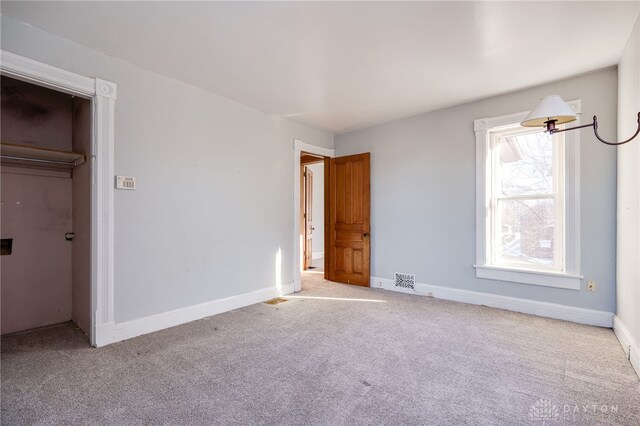 unfurnished bedroom featuring light colored carpet and a closet