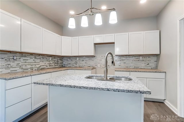 kitchen featuring sink, decorative light fixtures, white cabinets, and a center island with sink