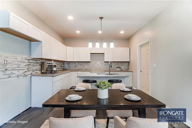 kitchen with tasteful backsplash, white cabinetry, light stone counters, and decorative light fixtures