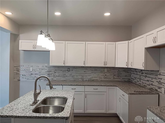 kitchen featuring sink, light stone counters, decorative light fixtures, decorative backsplash, and white cabinets