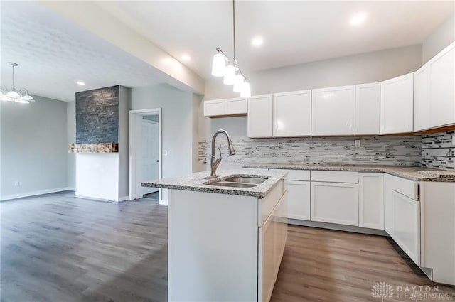 kitchen featuring sink, decorative light fixtures, an island with sink, decorative backsplash, and white cabinets