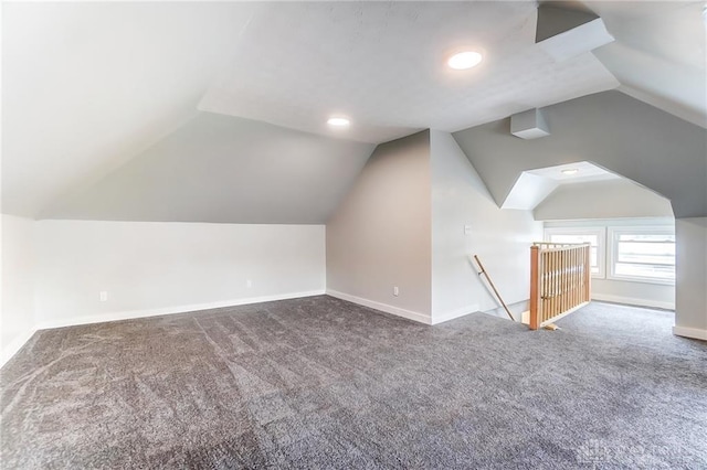 additional living space featuring dark colored carpet and vaulted ceiling