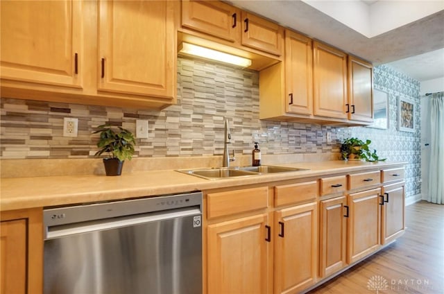 kitchen featuring sink, stainless steel dishwasher, light wood-type flooring, and decorative backsplash