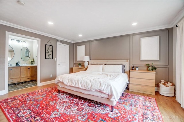 bedroom featuring crown molding, connected bathroom, and light hardwood / wood-style flooring