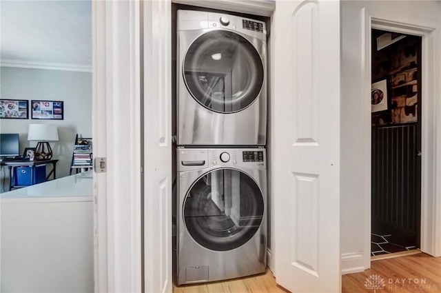 washroom with crown molding, stacked washing maching and dryer, and light hardwood / wood-style floors