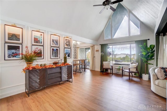 sitting room with wood-type flooring, ceiling fan, and high vaulted ceiling