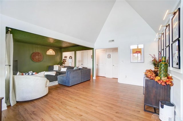 living room featuring high vaulted ceiling and light wood-type flooring