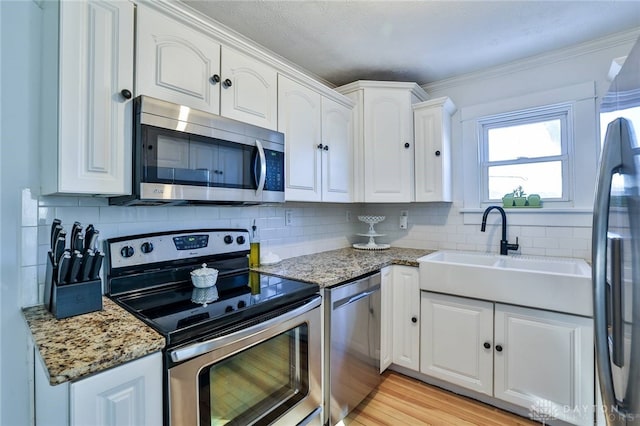 kitchen featuring appliances with stainless steel finishes, sink, dark stone counters, and white cabinets